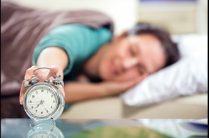 woman reaching for her alarm clock